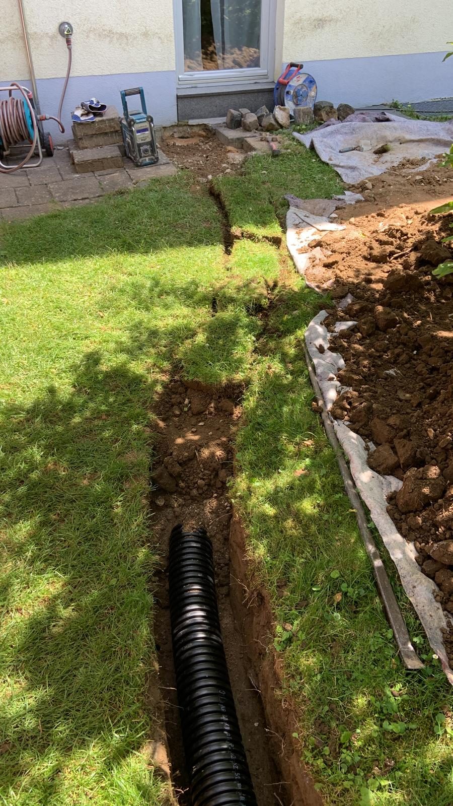 Drainagerohr im Graben entlang der Hauswand