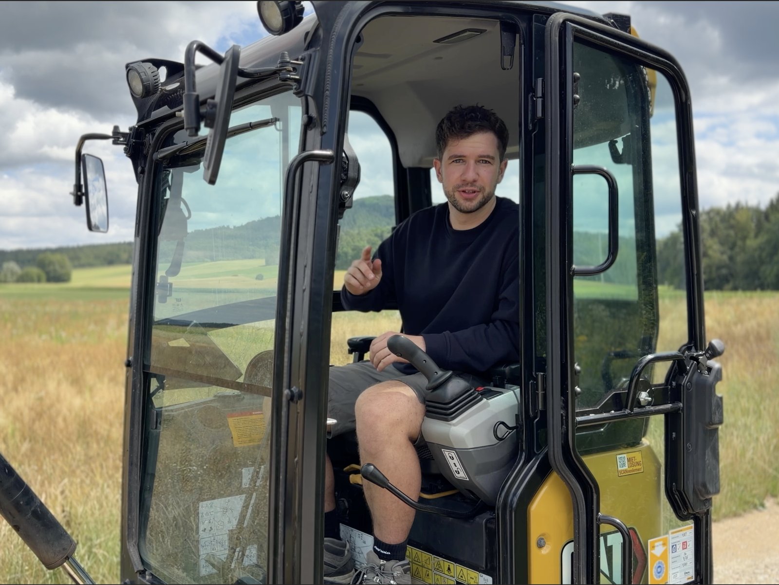 Flo, Gründer von Hubis Bagger-Service, in der Kabine des Minibaggers